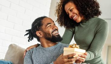 Woman giving a gift to a man while they are both smiling