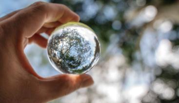 Person holding up a glass orb to see through it